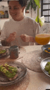 a man is sitting at a table eating avocado toast with a glass of orange juice .