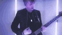 a man in a black jacket is playing a guitar in a room .