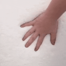 a close up of a person 's hand touching a pile of snow .