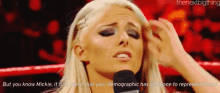 a blonde woman is talking into a microphone while holding her head .