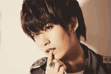 a young man with a ring on his finger is biting his nails .
