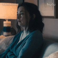a woman is sitting on a couch in front of a lamp and a sign that says paradise