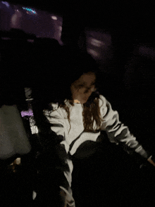 a girl in a white sweatshirt is sitting in the back seat of a car