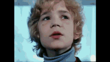 a young boy with blonde curly hair is looking up at the sky