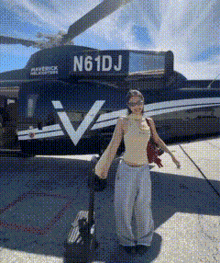 a woman is standing in front of a helicopter that says n61dj on the side