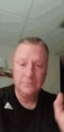 a man wearing a black adidas shirt is making a face .