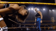 two women are wrestling in a ring and one of them is wearing blue pants