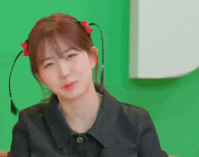a girl with pigtails and a red bow in her hair is making a face .