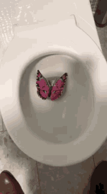 a pink butterfly is sticking out of the bottom of a toilet