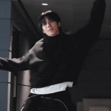 a man in a black hoodie is dancing in a dark hallway .