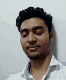 a man with his eyes closed is wearing a white polka dot shirt