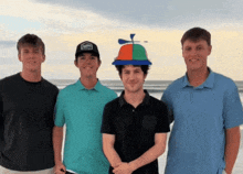 four young men are posing for a picture with one wearing a hat that looks like a propeller