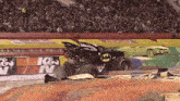 a monster truck with a batman logo on the side is driving down a dirt track