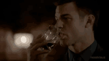 a man in a suit and tie is drinking from a glass .