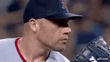 a baseball player wearing a hat and glove is about to throw a ball .