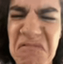 a close up of a woman 's face making a funny face with her eyes closed .