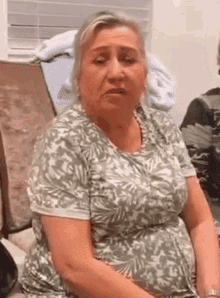 a woman in a green and white shirt is sitting in a chair and looking at the camera .