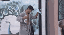 a man in a bathrobe is cleaning a window with a spray bottle