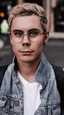 a man wearing glasses and a denim jacket