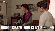 two women are standing in a living room with the words " noooo grazie non ce n'e bisogno " on the screen