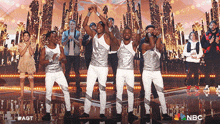 a group of men are dancing on a stage with a nbc logo in the corner