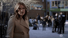 a woman in a trench coat is standing in front of a building with a sign that says " where children grow "