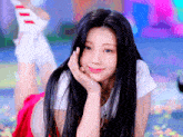 a woman with long black hair is laying on the floor with her hand on her chin