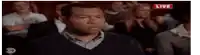 a man in a black sweater is sitting in a crowd of people watching a live event .