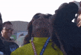 a woman wearing sunglasses and a lanyard that says new shepard is looking up at the sky .