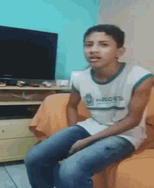 a young boy is sitting on a couch wearing a shirt that says hbcct