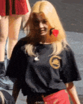 a woman with blonde hair is wearing a black shirt and red skirt