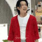 a man wearing a red cardigan and a white t-shirt is laughing .