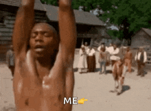 a man without a shirt is pointing at the word me in front of a group of people