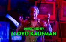 a man is standing in front of a screen that says directed by lloyd kaufman on it