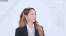 a group of young women are dancing together and one of them is wearing a suit and earrings .