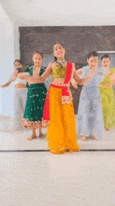 a group of young girls are dancing together in traditional indian clothing