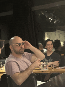 a man wearing sunglasses is sitting at a table with a fender shirt on