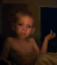 a shirtless child is sitting in front of a computer monitor