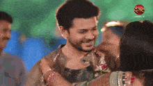 a man and a woman are hugging and smiling in front of a sign that says ' dangal tv '