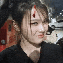 a woman with blood on her forehead is looking at the camera and smiling .