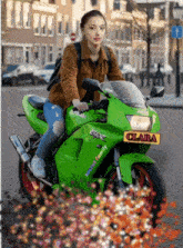 a girl is riding a green motorcycle with a yellow license plate that says clara