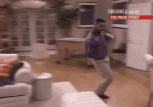 a man is dancing in a living room in front of a couch and a table .