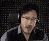 a man wearing headphones is sitting in a chair and making a funny face .