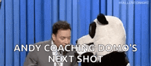 a man in a suit and tie is sitting next to a stuffed panda bear .