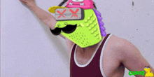 a man in a tank top has a green mask on his head with a x on it