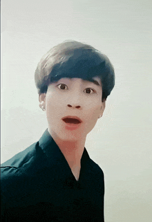 a young man in a black shirt is making a surprised face