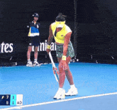 a woman is holding a tennis racquet on a tennis court with a scoreboard that says 7 1 5 1 ad