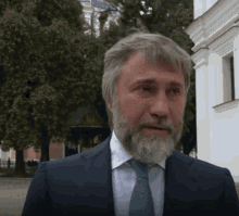 a man with a beard is wearing a blue suit and a green tie