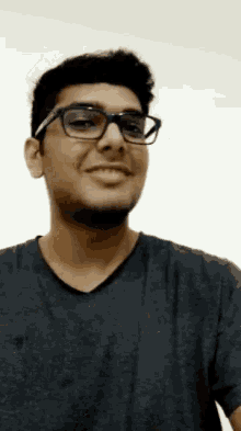 a young man wearing glasses and a black shirt is smiling and looking at the camera .
