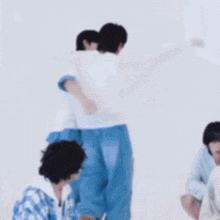 a group of people are hugging each other in a room while a man is carrying another man on his shoulders .